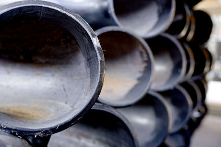 Black metal pipes and adapters of different diameters for gasification or water supply. Industrial background with copy space. Storage warehouse for metal productsの写真素材