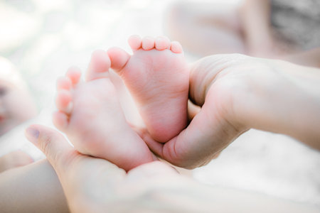 The mother gently holds her babys small feet in her hands. The love and feelings of a parent for their newborn child.の写真素材