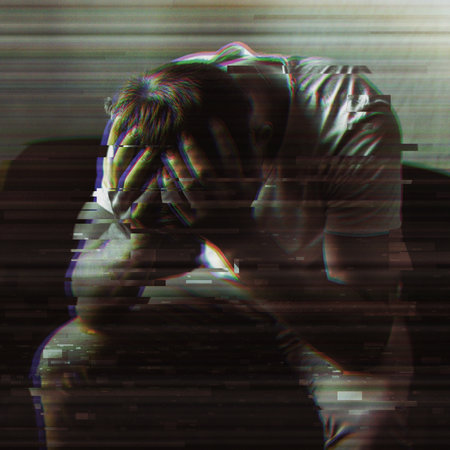 Mens problems. A young man sits on a chair and holds his head with his hands.の写真素材