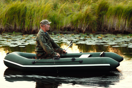 An elderly man is sailing on a rubber boat with oars on a calm river. The inspector checks the...
