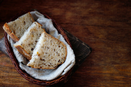 Pieces of sliced bread lie in a wicker basket on a wooden table. Fresh homemade baking of yeast-free...