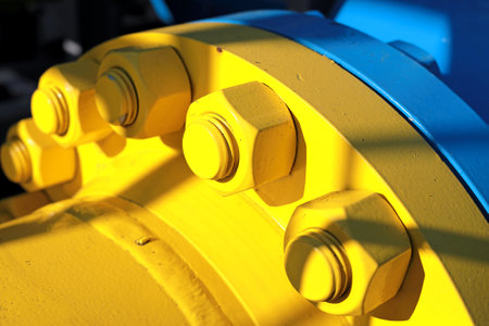 Two blue and yellow gas pipes are connected by large bolts and nuts. Background for suppliers of gas products and pipes.の写真素材