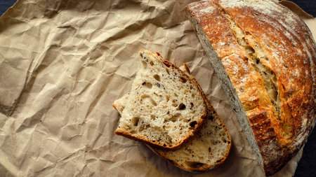 This is a loaf of fresh crusty bread with cereals on sourdough. Yeast-free homemade cakes lie on...