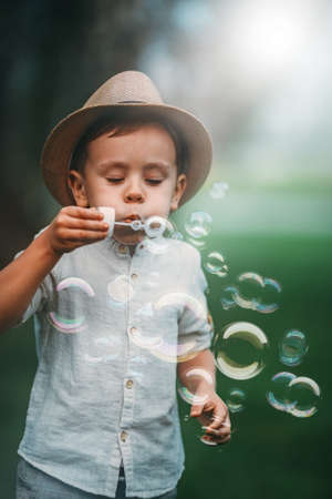 The child diligently blows a lot of soap bubbles in the park.の写真素材
