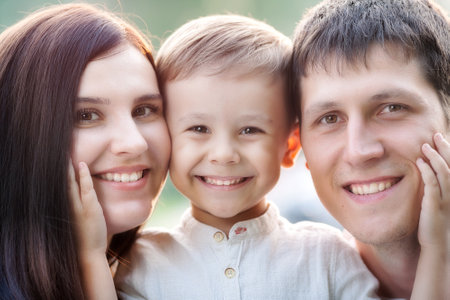 Close-up portrait of a happy young family. Mom, dad and little son look at the camera and smile.の写真素材