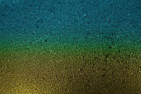 Small drops of water or condensate on the metal surface are yellow and blue. Abstract background for...