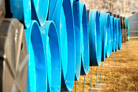 Large-diameter pipes with plugs lie in an open warehouse on a summer day. Storage and supply of...