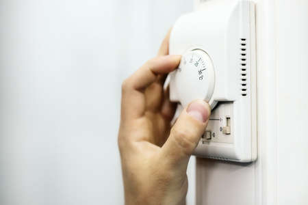 Human hand on the air conditioner temperature controller. Service for the installation and...