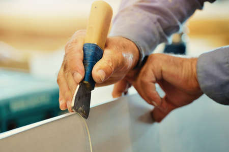 The hands of an elderly carpenter and a tool while working in close-up. Processing of a wooden plate...