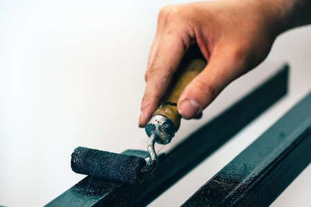 Painting of metal pipe with paint roller. The hand of a painter with a roller close-up. Photos at workの写真素材