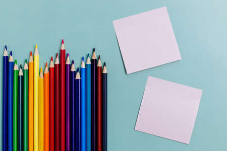 Colored pencils and a sheet for notes lie on a blue background. Top view. Background to-do list back to school. Minimalistic and stylish creative backdrop.の写真素材