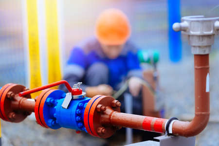 Crane connection of pipe for gasification. The specialist inspects and maintains the gas equipment at the industrial facility on a summer day. Blurry background.の写真素材