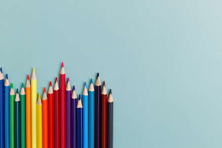 Colored sharpened pencils lie on a blue background with space for copying. School supplies or school...