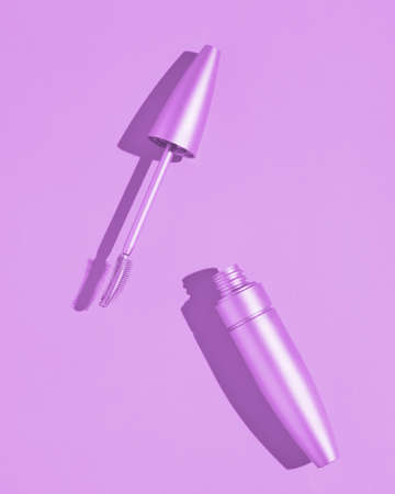 Open tube of mascara. Purple background. Advertising photography aesthetics and minimalism of cosmetics for eyelashes. Fashionable picture with a hard shadowの写真素材