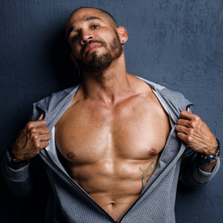 Studio portrait of a muscular African American or Latino with a naked torso. Male strength and potency. Brutal man with tattoos on his body. Strong muscles.の写真素材