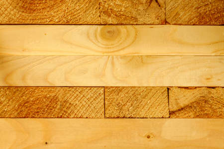 Solid background of new wooden bars. Yellow wood. Material for construction.