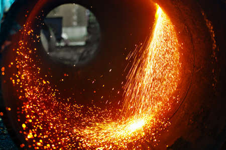 Cut a metal pipe of large diameter and sparks fly. Industrial background.の写真素材