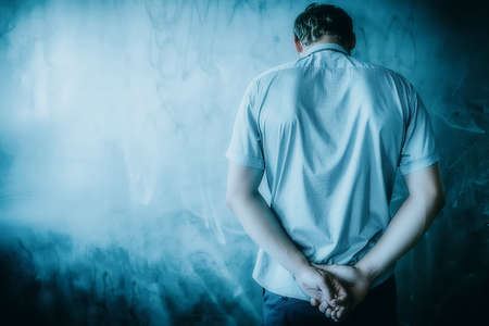 The man rested his head against the wall. Standing facing the wall. The concept of deadlock and hopeless situation. Male crisis and despair. Background with space to copy.の写真素材