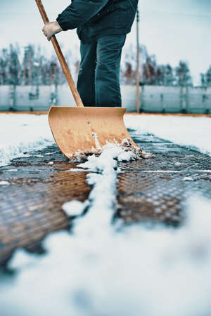 Janitor clears area of snow with wooden shovel. Cleaning streets after snowfall and blizzard. Background.の写真素材