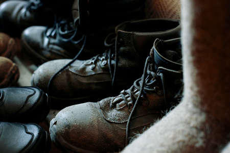 Many old work boots stand together. Old worn construction boots of workers. Background. Real scene....