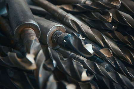 Used drill bits on metal close-up. Set of steel drills in lathe workshop. Background.