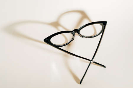 Black womens glasses in fashionable frame lie on beige background. View from above. Object to improve vision. Advertising background for store glasses and optics.の写真素材