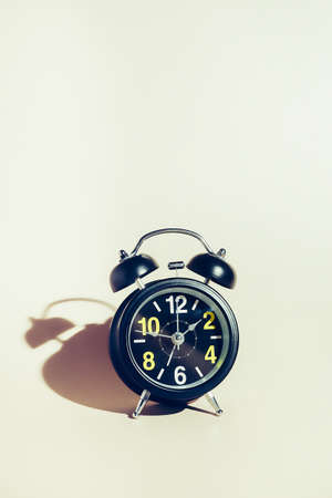 Black alarm clock with dial on beige background. Concept of time and timing with space for copying....