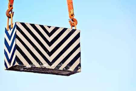 Control load is lifted by slings against sky. Concept of training slingers. Striped heavy box rises up. Backgroundの写真素材