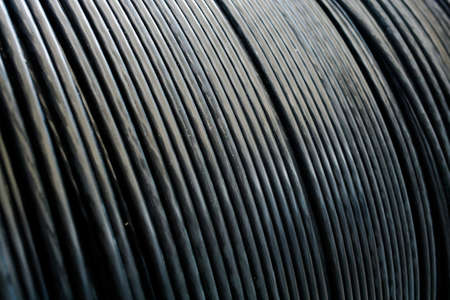 New black power cable is wound on wooden coil. Background. Cable for laying underground.