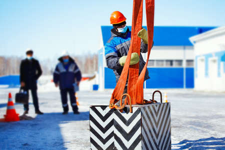 Working slinger passes exam on lifting loads. Real scene. Commission evaluates skill of slinger....