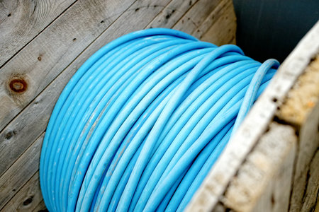 New blue power cable is wound on wooden coil. Background. Cable for laying underground.の写真素材