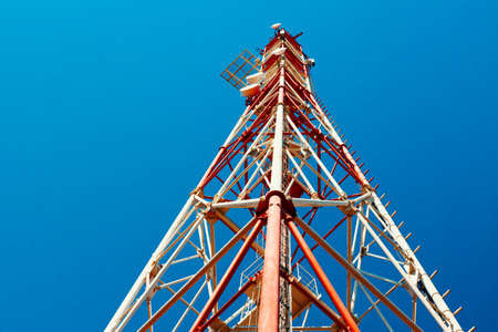 The communication tower stands against the sky with a bottom-up view. Close-up
