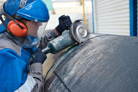 Linear fitter or pipeliner removes plastic insulation from large-diameter pipe with angle grinder....