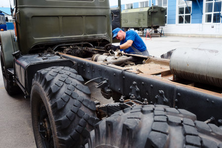 Mechanic in overalls repairs truck on summer day outside. Urgent repair of trucks. Authentic workflow..の写真素材