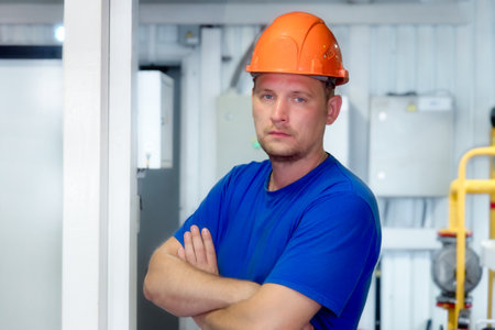 Portrait of engineer in construction helmet and work clothes on industrial background inside...