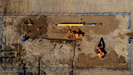 Aerial view excavator and construction workers working on construction site in open field. Pipe laying in trench for gasification. Top point of shooting. Repair and restoration of natural gas supply..の写真素材