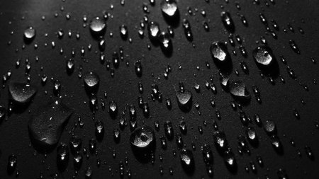 Round drops of water on dark background. Through transparent drops of water pass rays of light. View from top. Beautiful back for screensaver. Abstract background..の写真素材