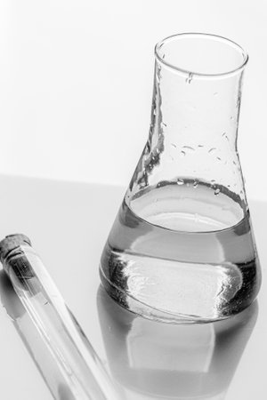 Glass medical test tube and liquid flask stand on mirror table. Experiment or laboratory analysis. Background..の写真素材
