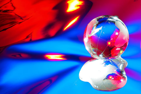 Glass ball in form of planet or globe on colored abstract background. Glass globe with reflection. Blue-red background..の写真素材