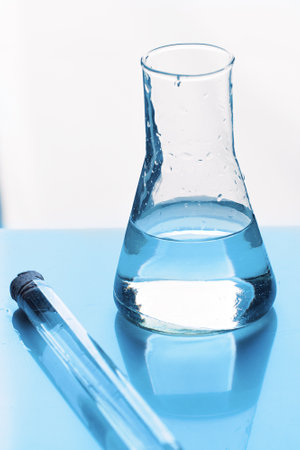 Glass medical test tube and liquid flask stand on mirror table. Experiment or laboratory analysis. Background..の写真素材
