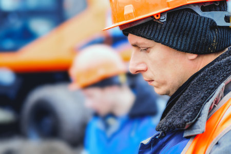 Engineer in helmet looks down. Large portrait on side. Caucasian worker in construction clothing...