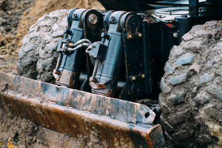 Wheeled tractor with shovel clears ground on cloudy rainy day. Dirty bulldozer shovel close-up..の写真素材