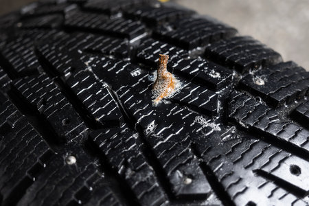 Nail sticks out of cars tire. Car wheel puncture. Close-up..の写真素材