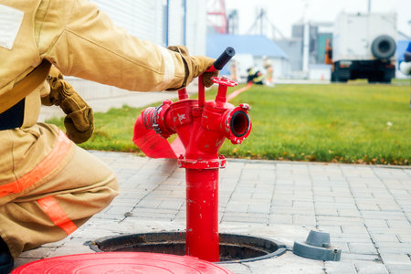 Firefighter sits next to fire hydrant. Back view. Firemen training.の写真素材