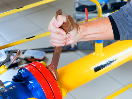 The worker tightens the nut of the gas equipment with an adjustable wrench. hands close up. Diagnostics of gas equipment. Preparation of a gas boiler for the heating season.の写真素材