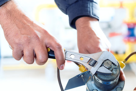 Worker tightens nut of gas equipment with adjustable wrench. hands close upの写真素材