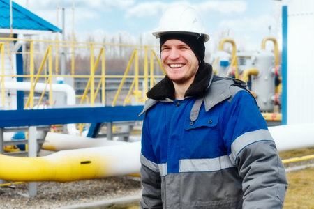 Portrait of positive and happy worker or builder in hard hat on winter day at industrial site.の写真素材