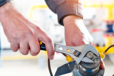 Worker tightens nut of gas equipment with adjustable wrench. hands close upの写真素材