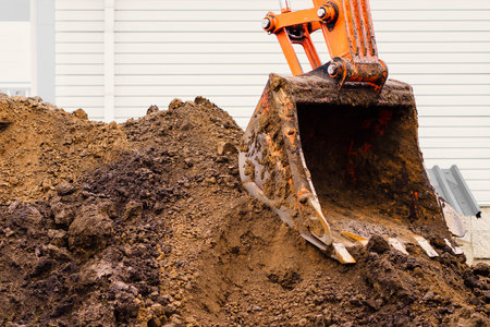 Dirty excavator bucket and pile of clay with earth close-up. Digging trench or pit. Construction theme.の写真素材