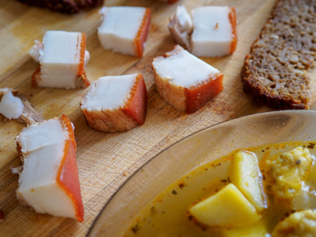 Simple food. Soup and pieces of lard lie on a wooden table. Close-up. View from aboveの写真素材